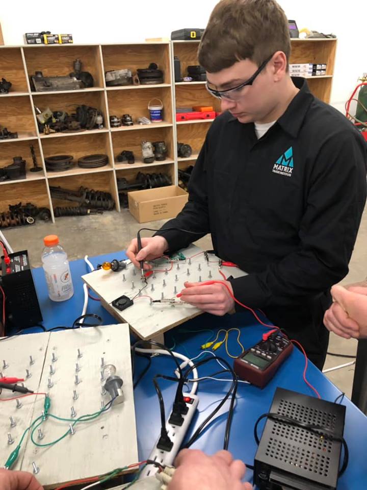 Auto mechanic student shows perseverance operating on a circuit board, which is one of the automotive technician skills needed.